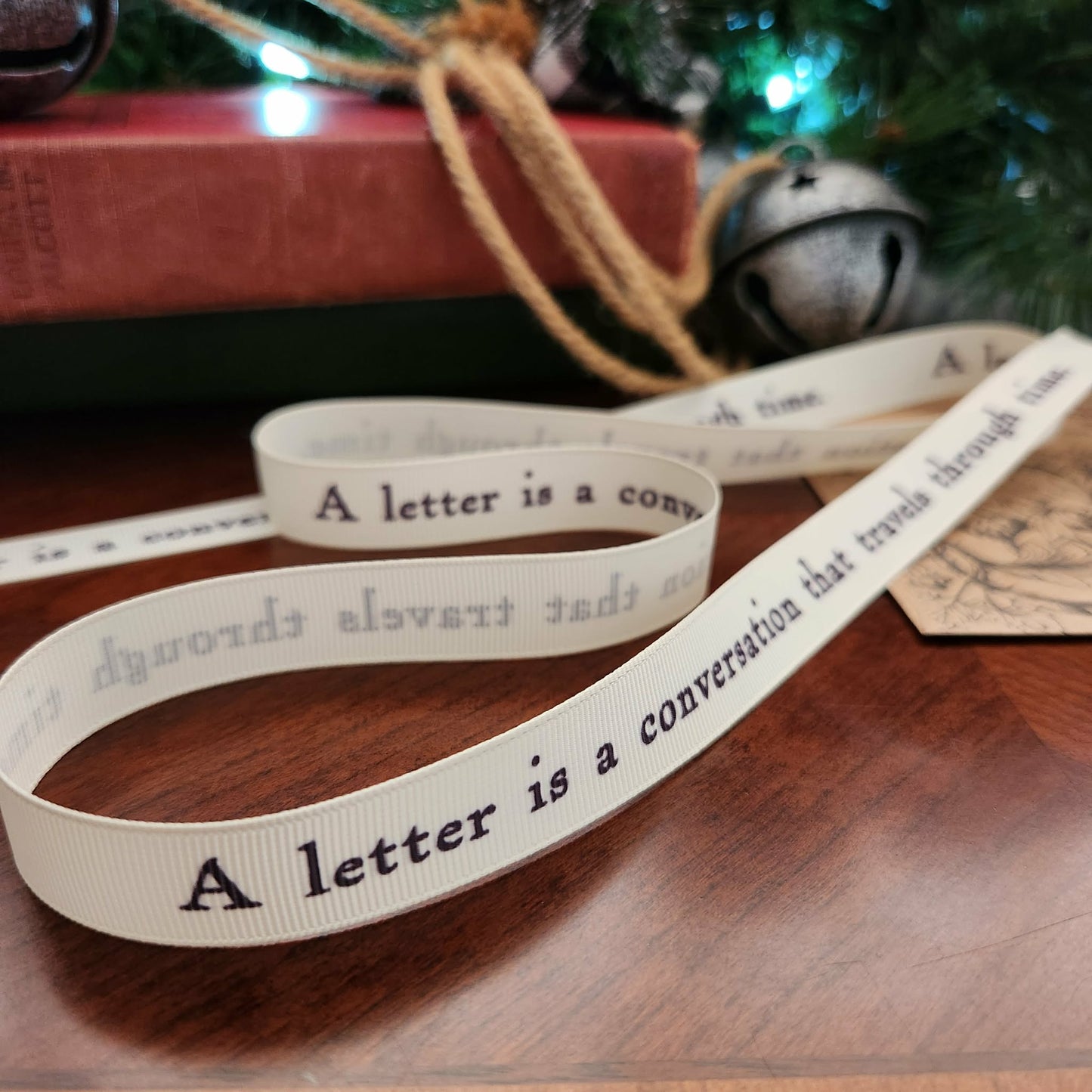 Decorative ribbon with text on a wooden surface with a Christmas tree in the background