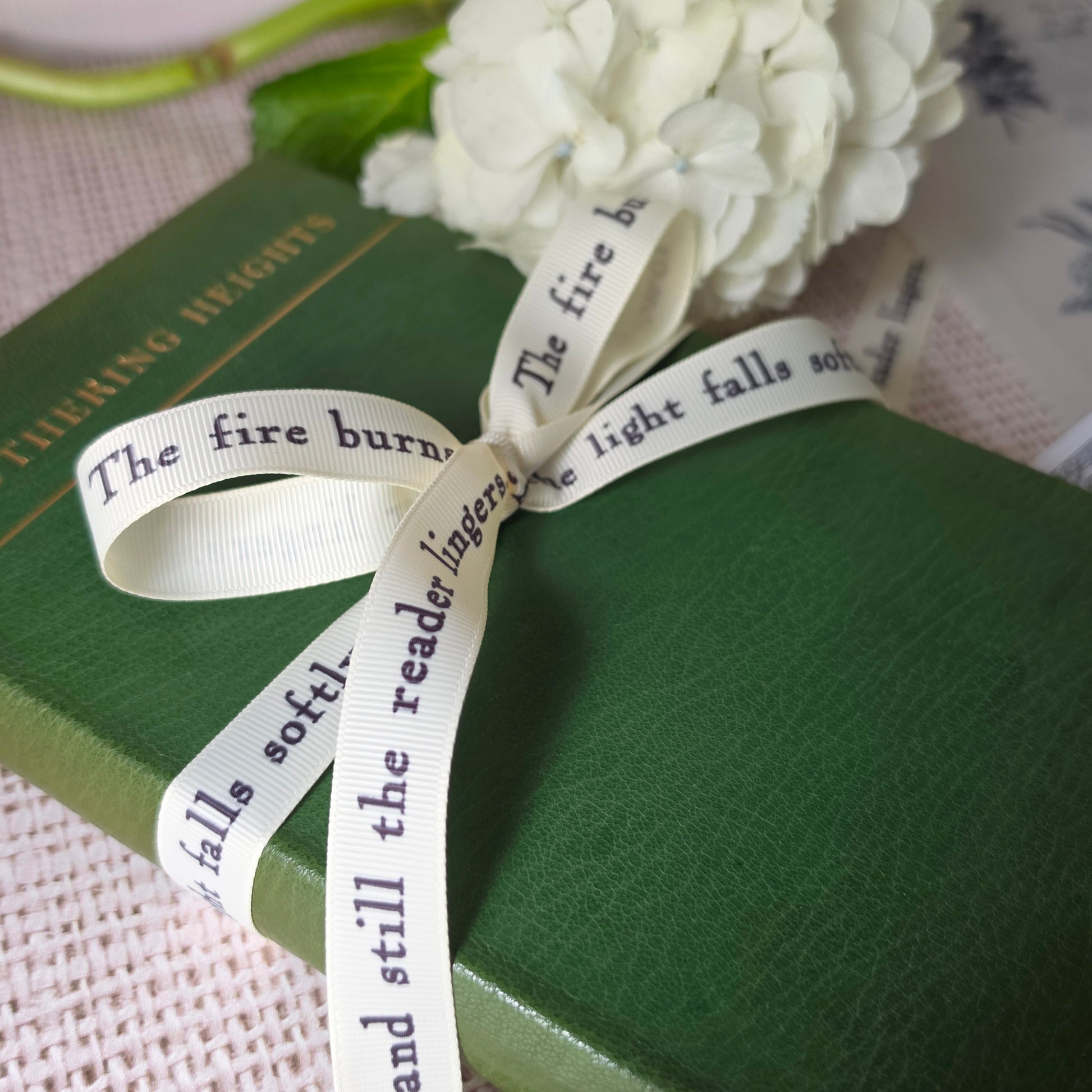 Cream grosgrain ribbon printed with literary quote tied around green vintage book