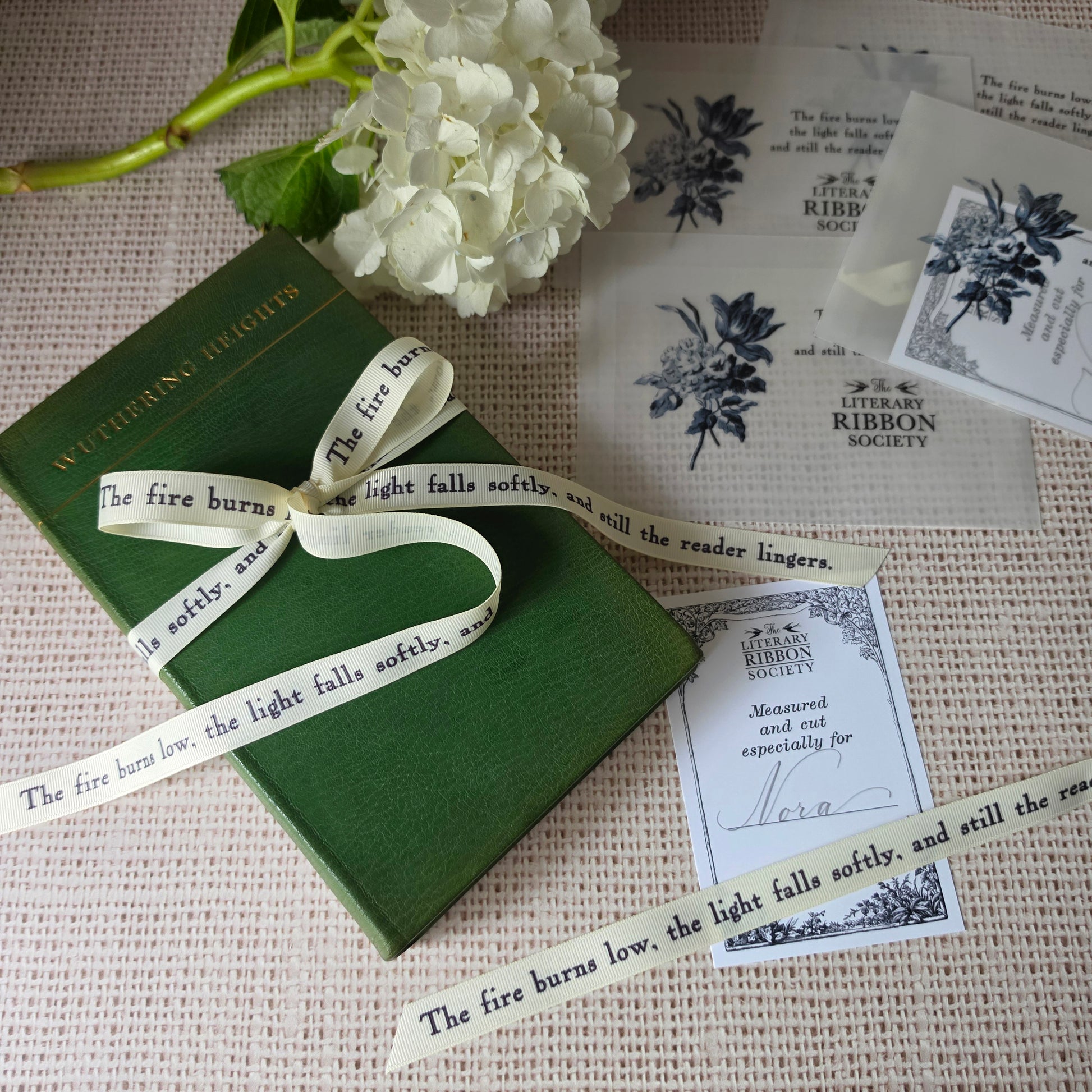 Literary ribbon with printed quote displayed beside personalized cards and vellum sleeves