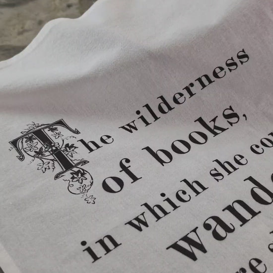 The Wilderness of Books literary tea towel draped over a bowl of lemons on a kitchen counter