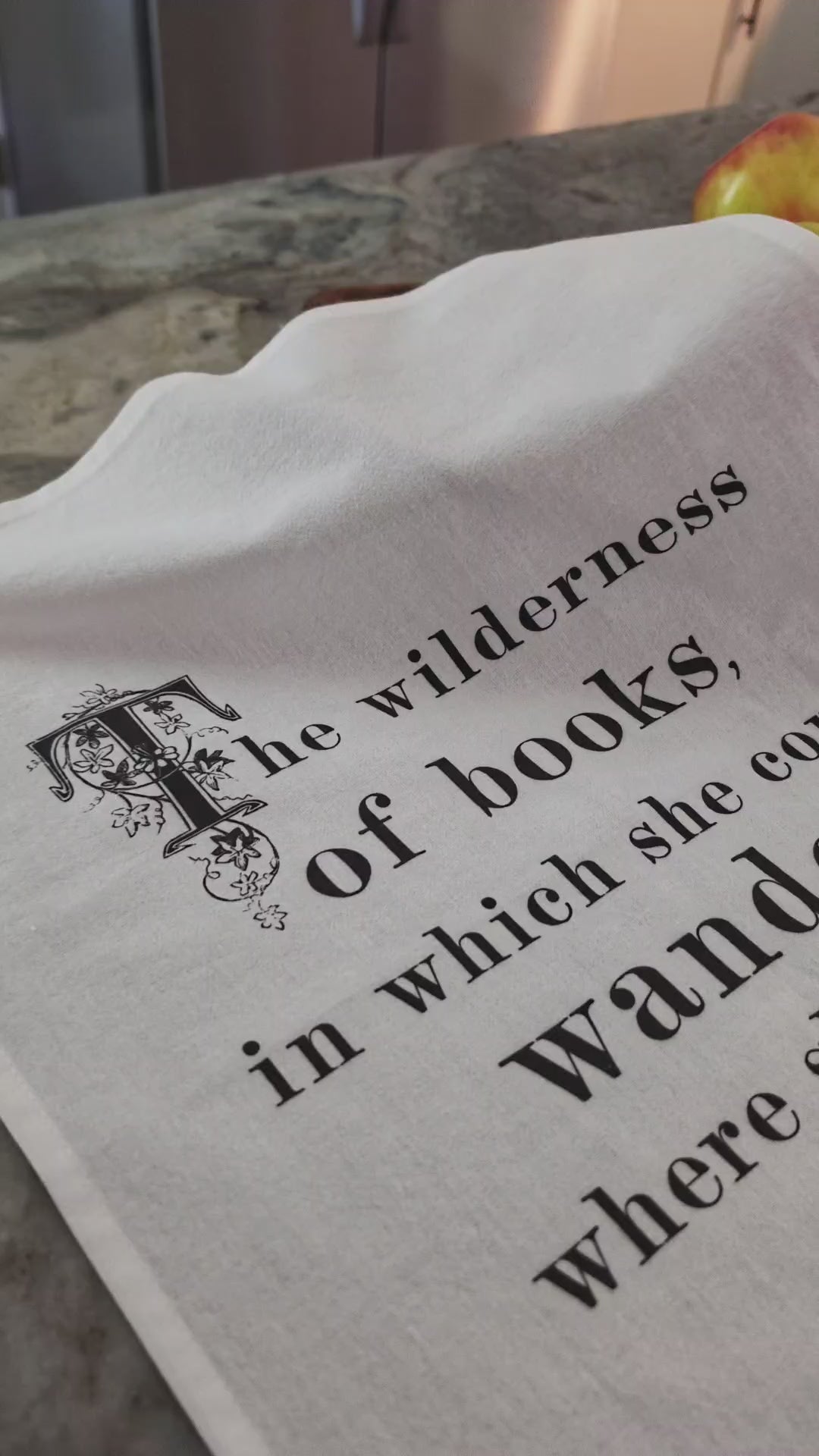 The Wilderness of Books literary tea towel draped over a bowl of lemons on a kitchen counter